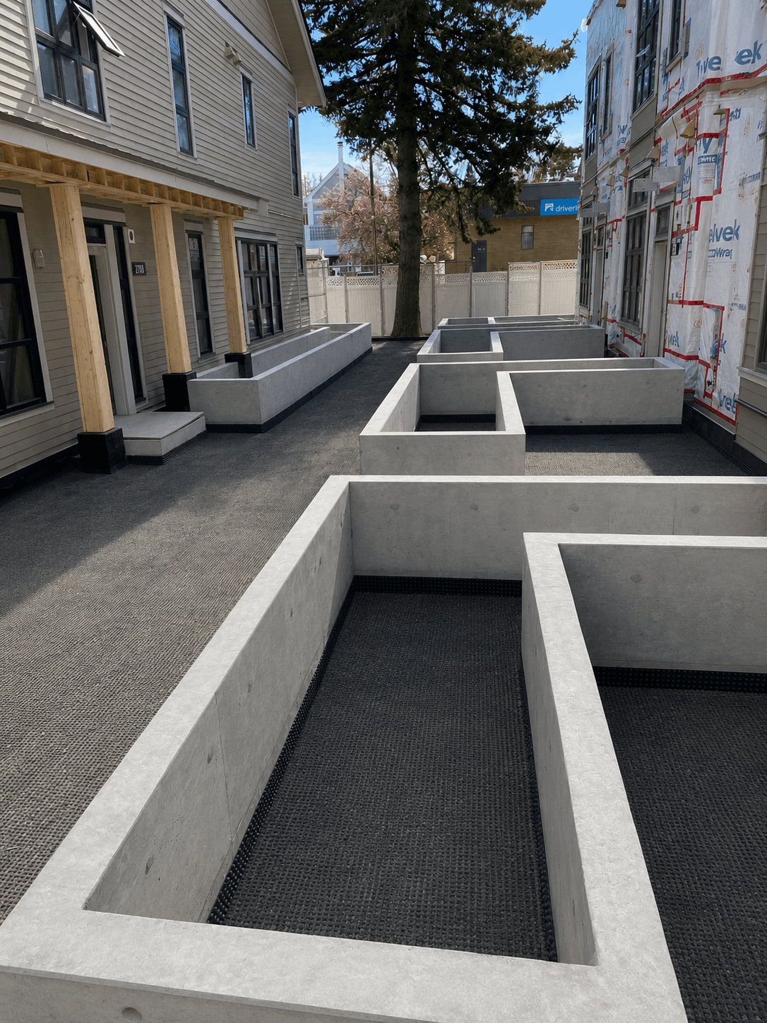 Precast concrete planter walls lining a courtyard walkway between townhome units