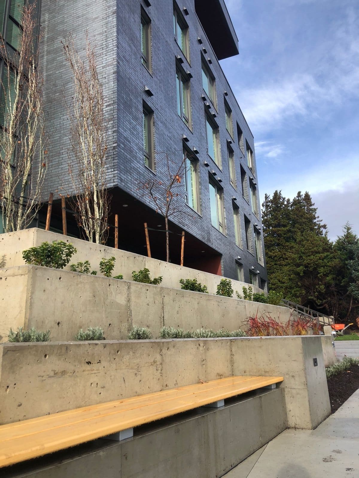 Tiered concrete retaining walls with built-in bench seating in front of a multi-unit building