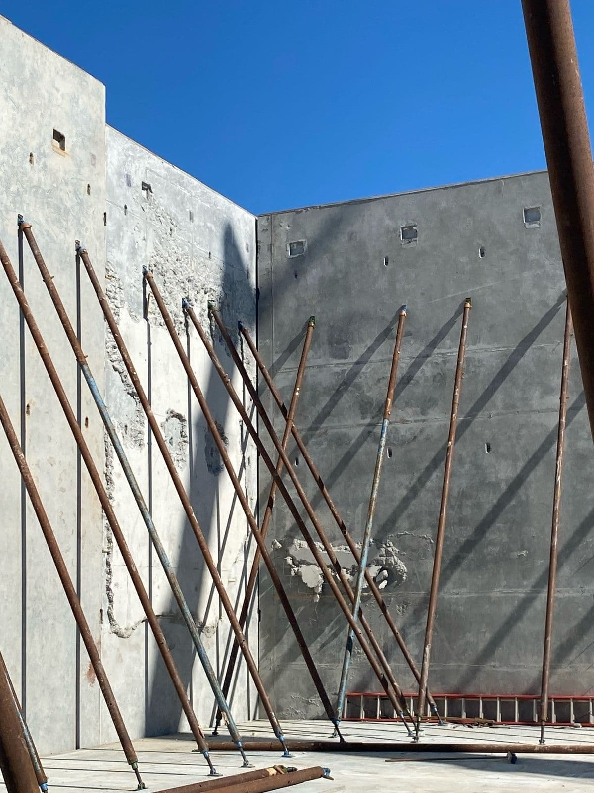 Corner of tilt-up concrete panels braced with diagonal shoring poles