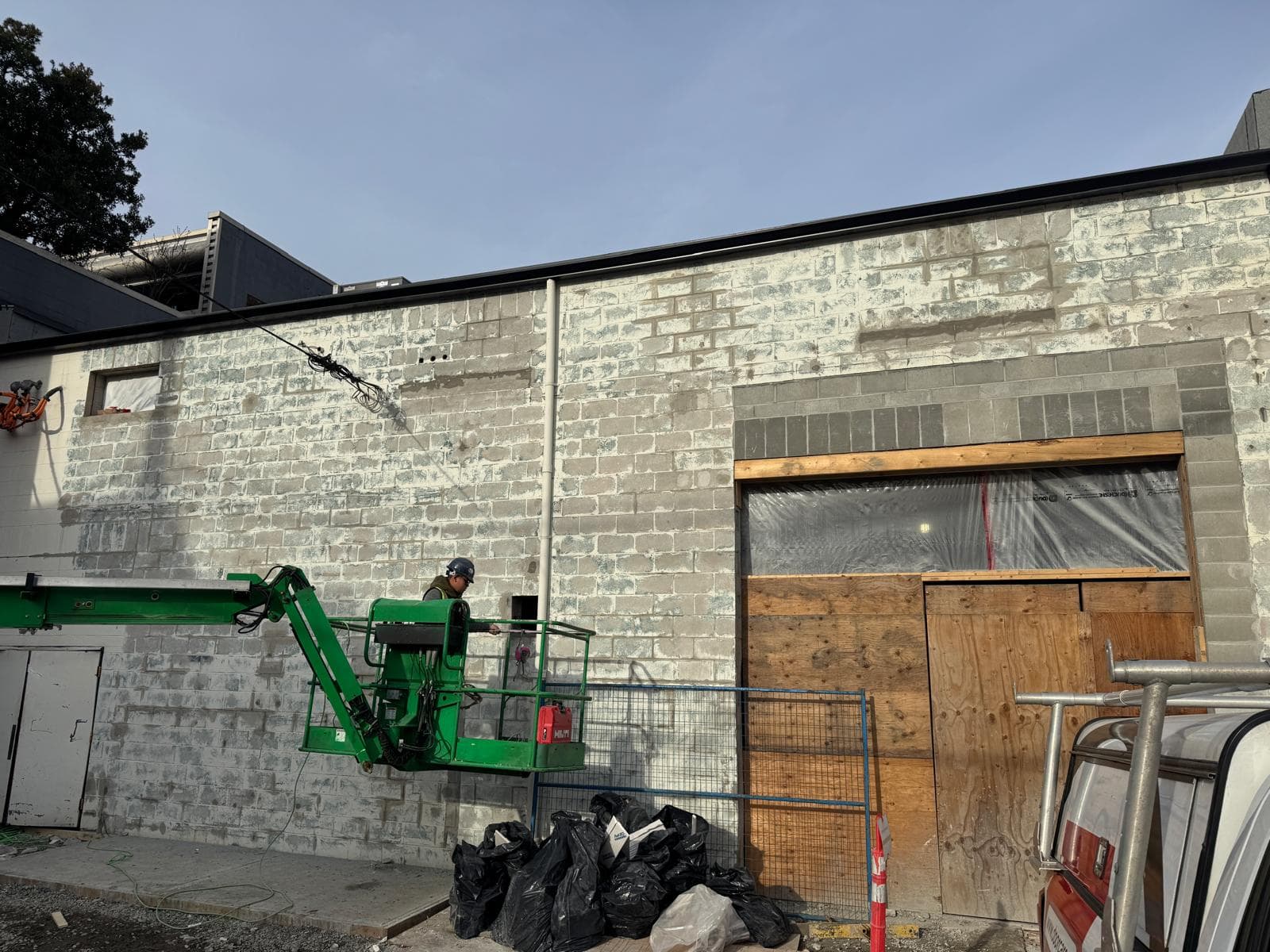 Worker in a boom lift grinding back a stained concrete block exterior wall